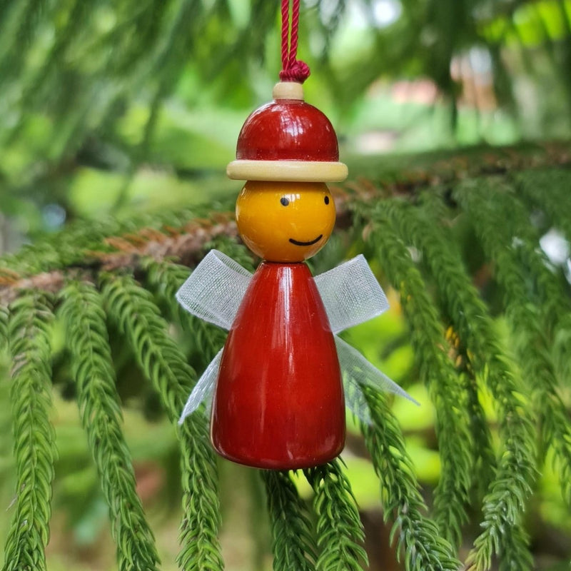 Decorative wooden angel hanging on a green tree branch