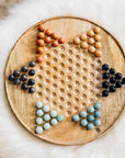 Wooden chinese checkers board with colored marbles on a soft white surface