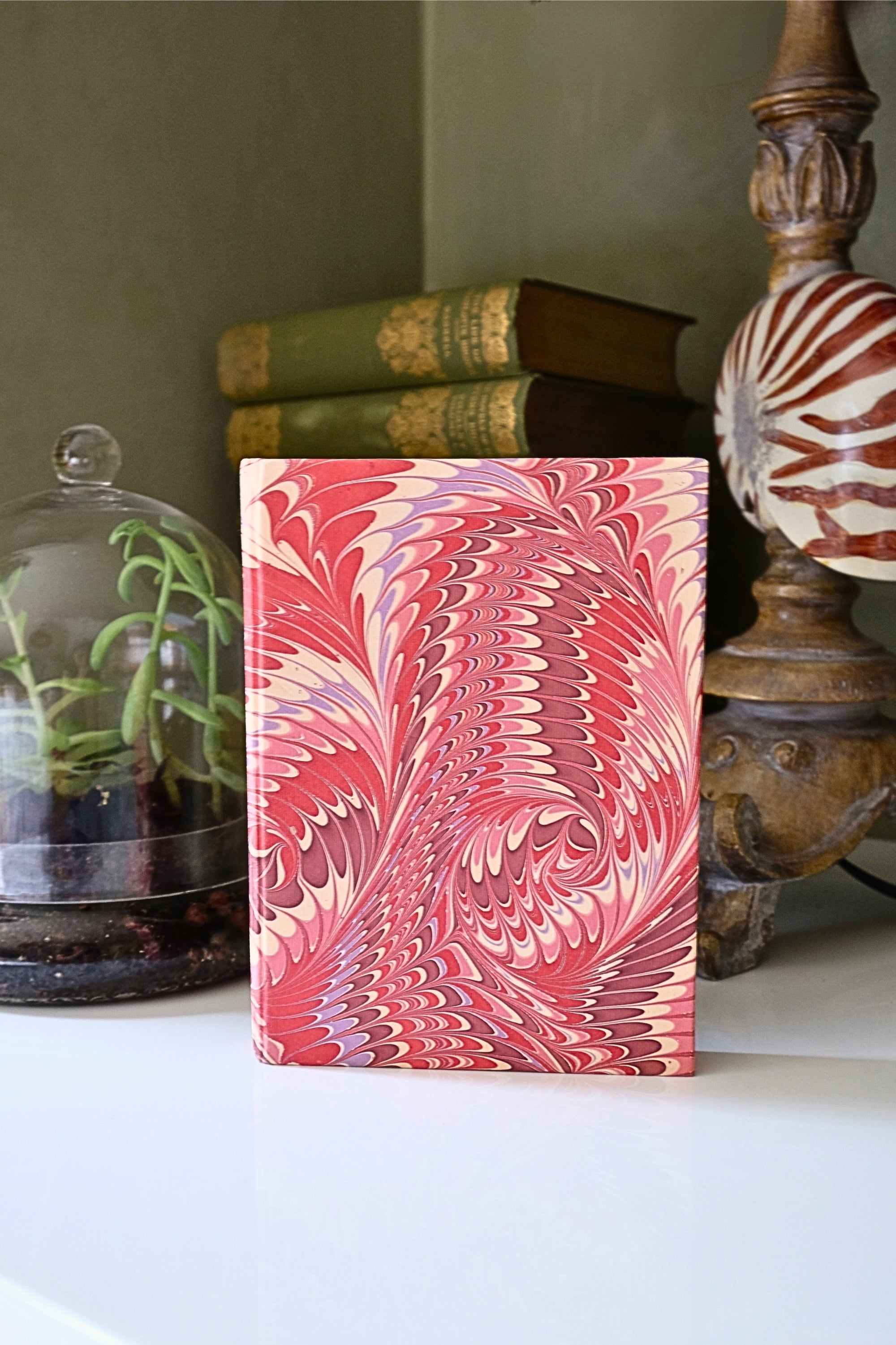 Marbled pink and white notebook on a surface with decorative items in the background