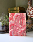 Marbled pink and white notebook on a surface with decorative items in the background