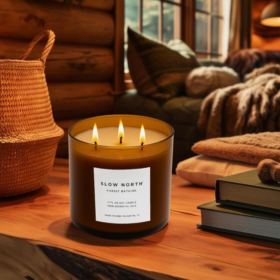 Candle labeled 'Slow North' on a wooden surface with a cozy indoor setting.