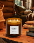 Candle labeled 'Slow North' on a wooden surface with a cozy indoor setting.