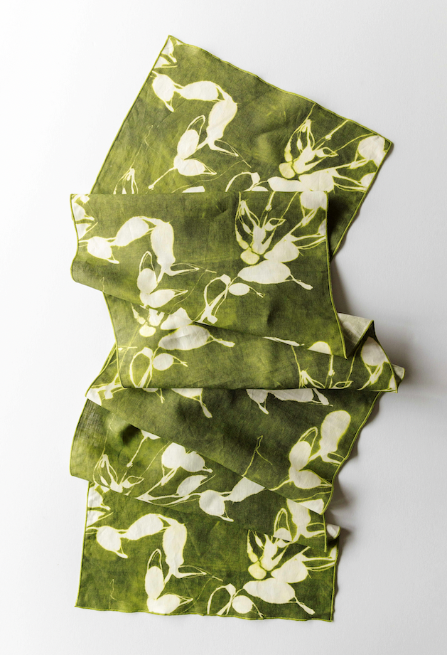 Green fabric with white floral pattern folded on a white background