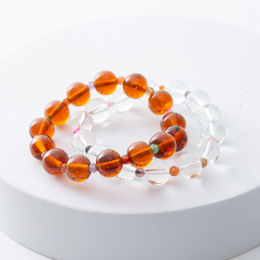 Two amber beaded bracelets on a white surface