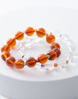 Two amber beaded bracelets on a white surface