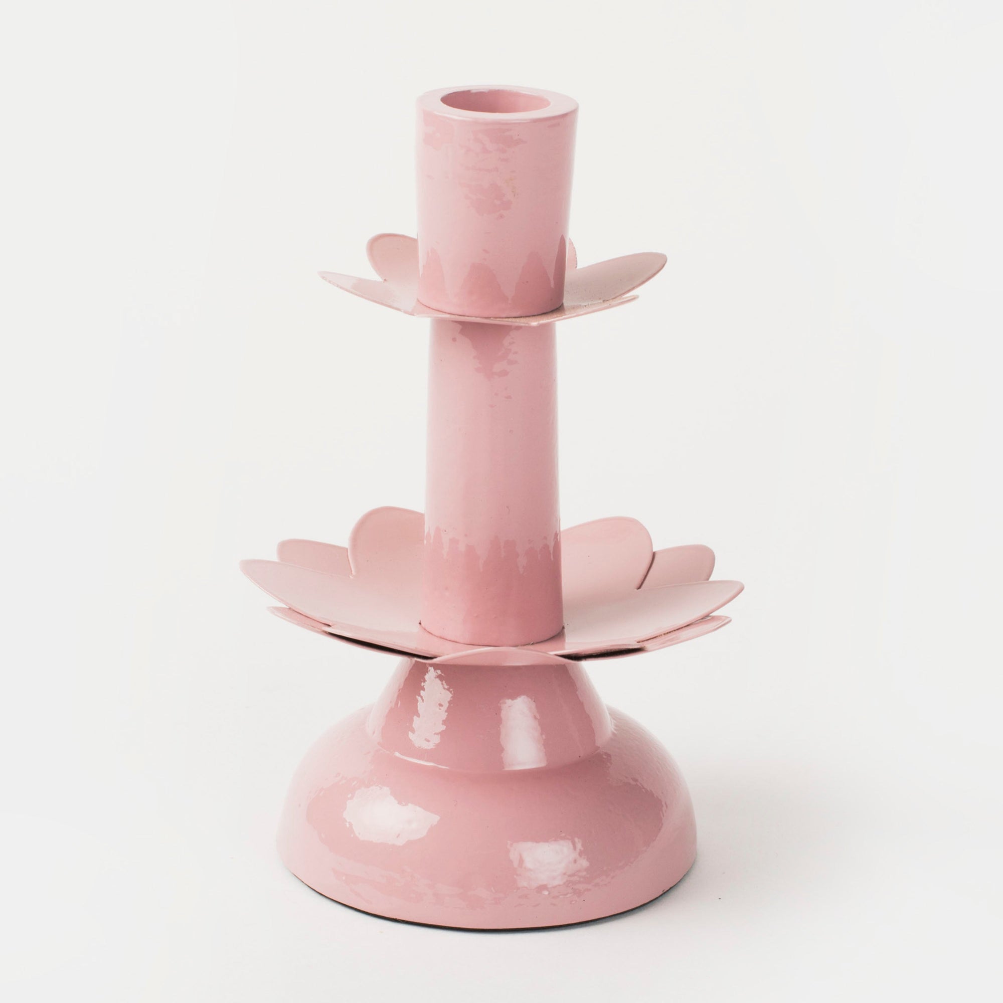 A pink metal taper candleholder with a design resembling a lotus flower