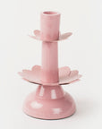A pink metal taper candleholder with a design resembling a lotus flower