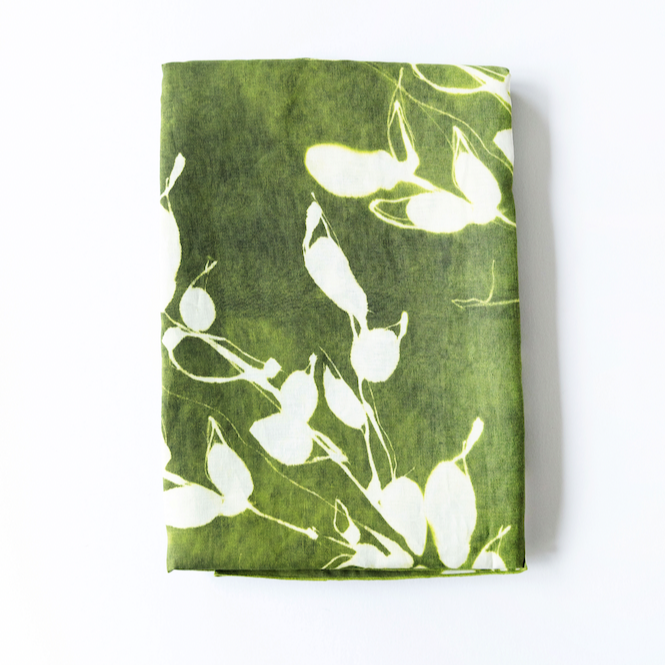 Green linen table runner with white floral pattern on a white background