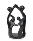 A black stone sculpture depicting a family unit of four with multiple members embracing each other