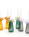 Set of colorful glass candle holders with candles on a white background