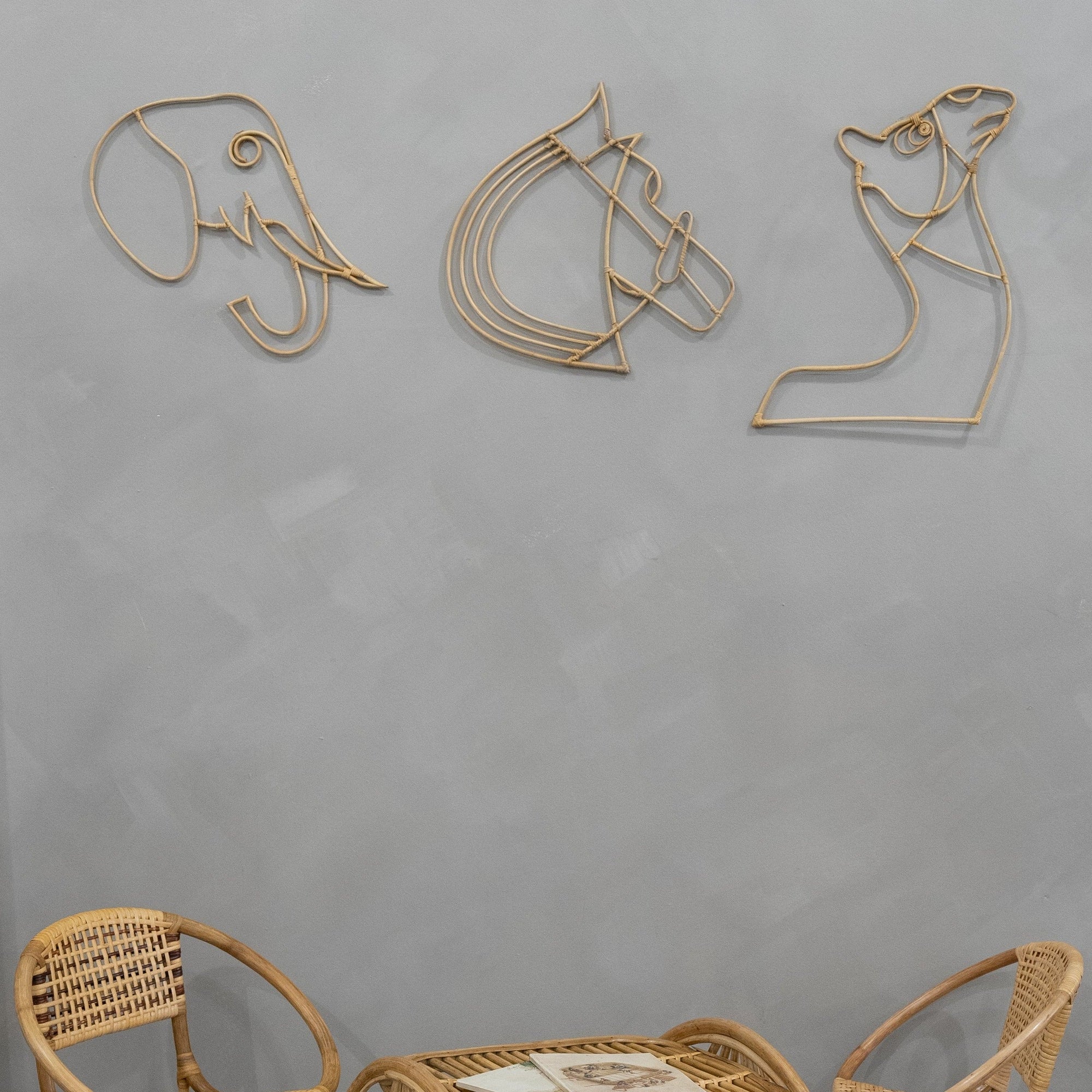 Three Rattan wall art pieces on a gray wall with wicker chairs at the bottom.