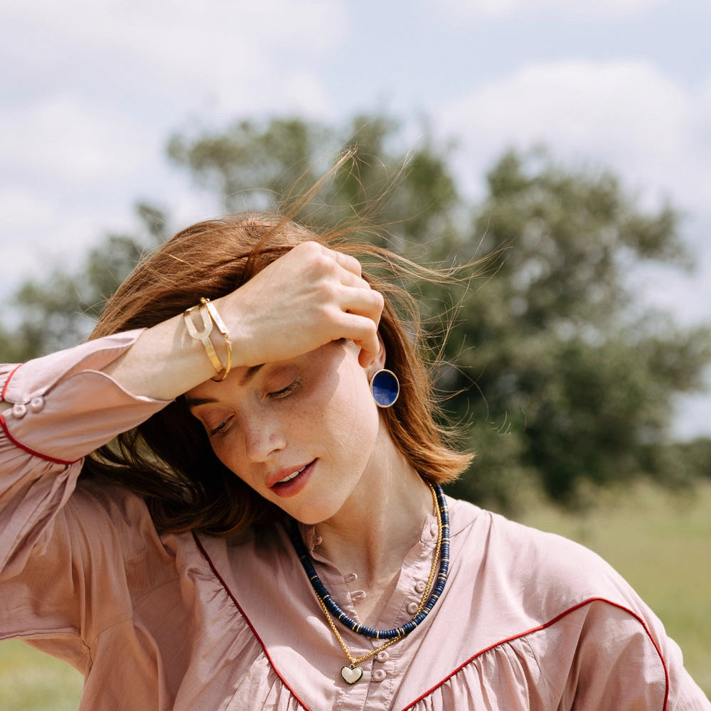 Woman in a pink blouse with red trim outdoors on a sunny day