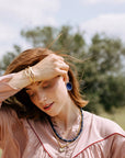 Woman in a pink blouse with red trim outdoors on a sunny day