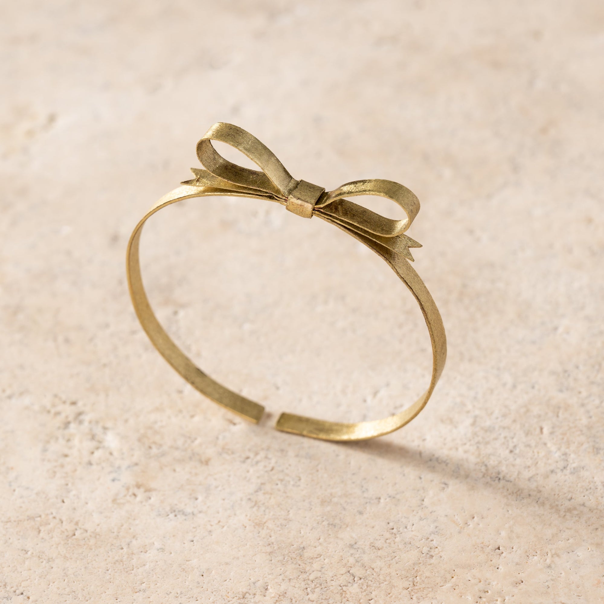 Gold bracelet with a bow design on a beige background