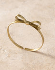 Gold bracelet with a bow design on a beige background