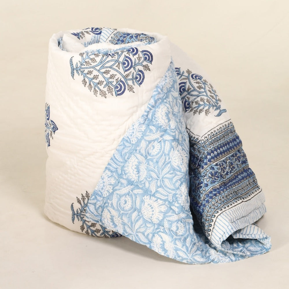 Folded quilt with blue and white floral patterns on a beige background