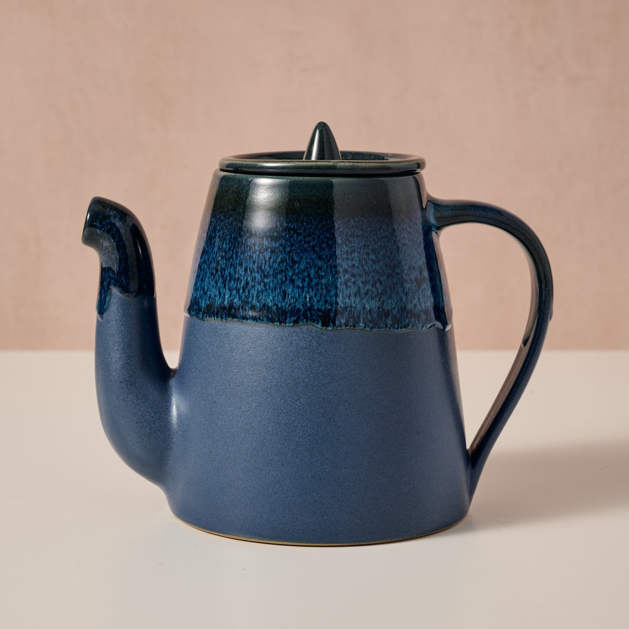 Blue ceramic teapot with a textured finish on a beige background
