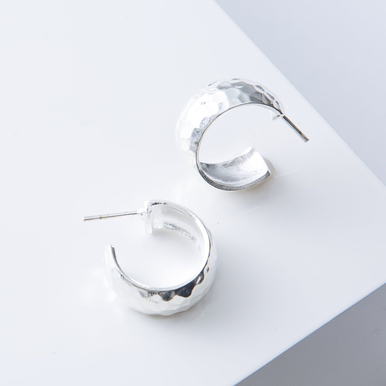 Silver hoop earrings on a light gray surface