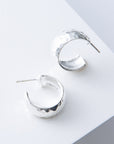 Silver hoop earrings on a light gray surface
