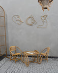 Rattan furniture set with decorative wall art in a room with a patterned rug.