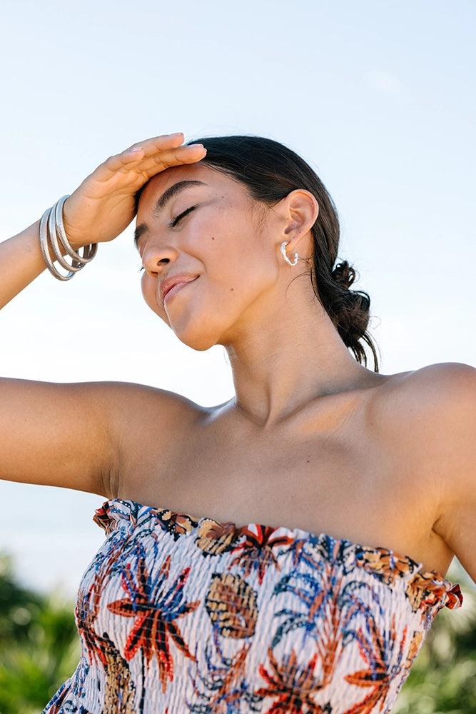 Woman wearing a floral strapless top with a blurred natural background