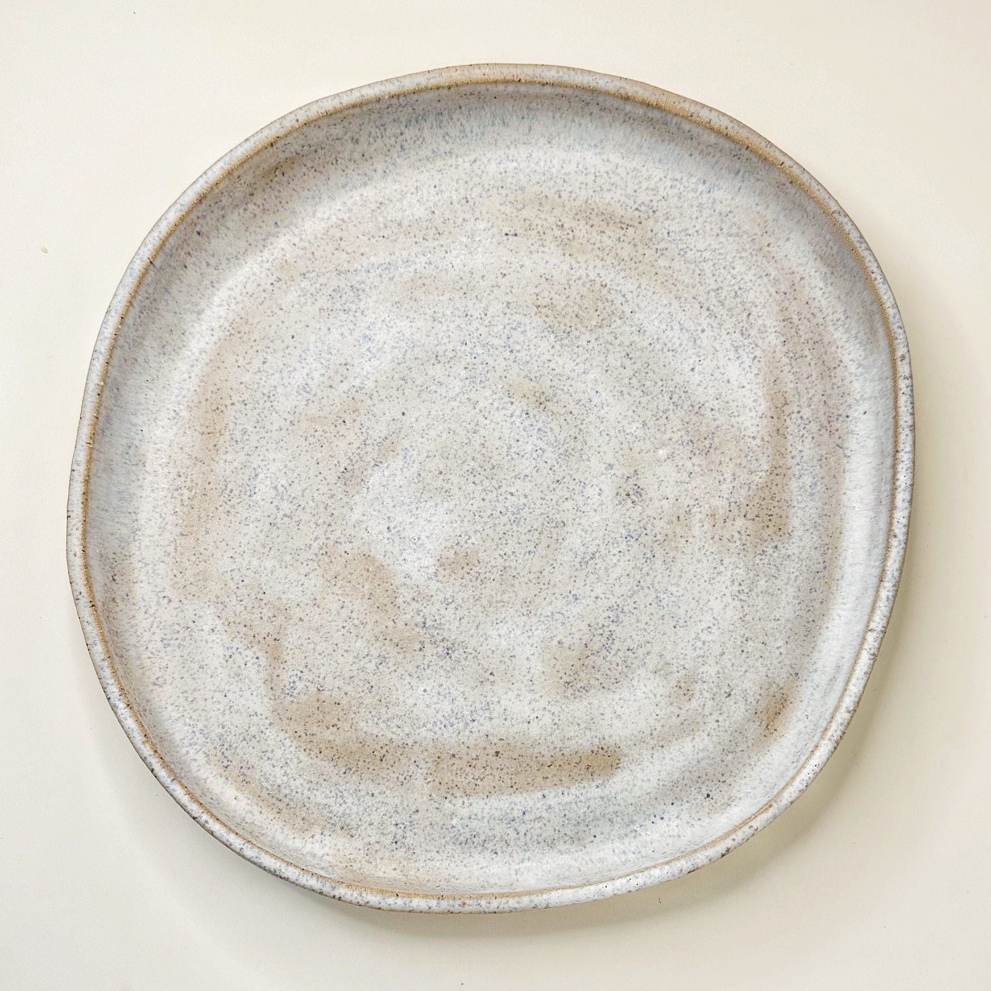 Round ceramic plate with a textured surface on a light beige background