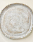 Round ceramic plate with a textured surface on a light beige background