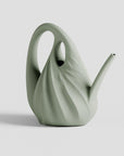 Green ceramic watering can on a light gray background