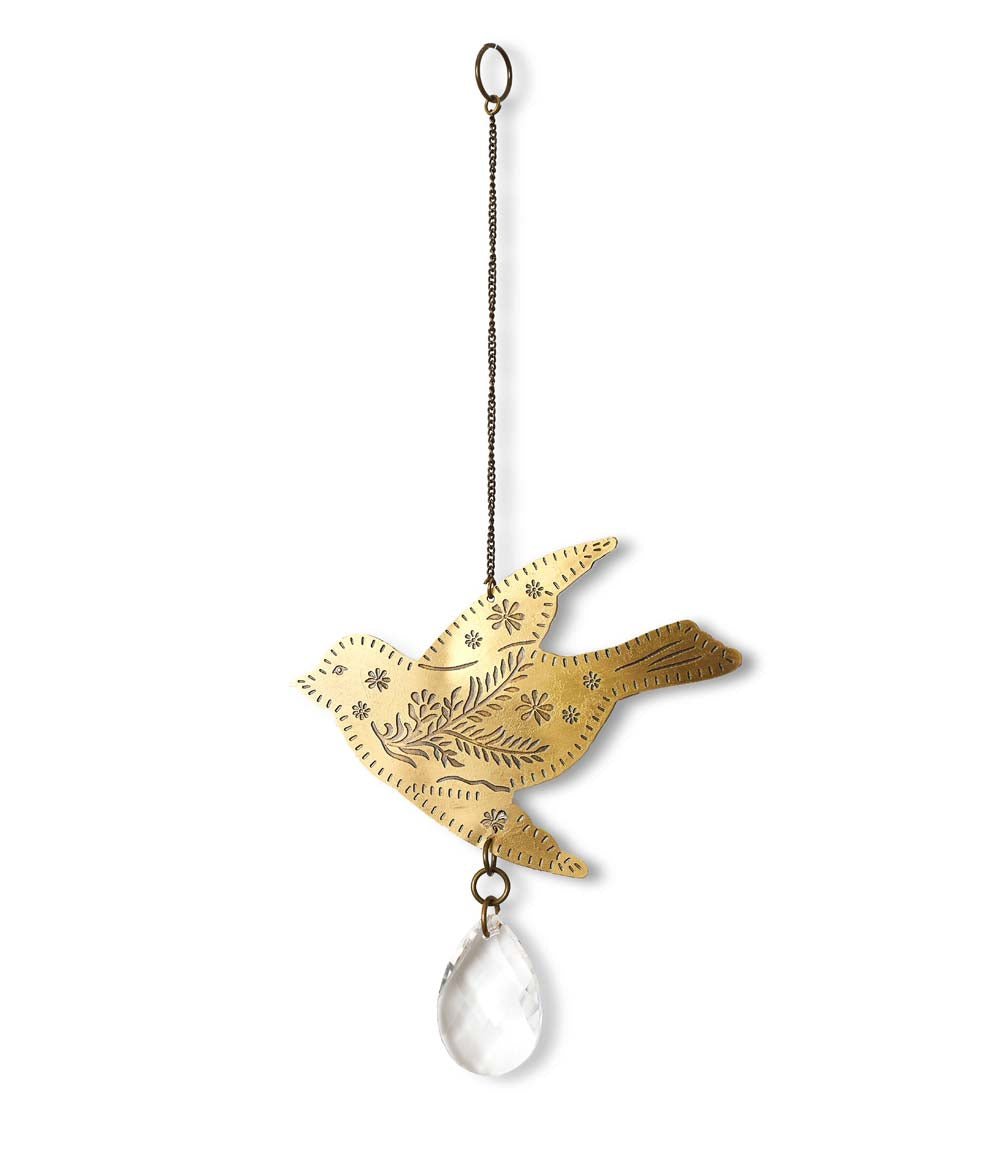 A brass suncatcher in the shape of an engraved bird with a teardrop crystal at the bottom, hanging from a wire.