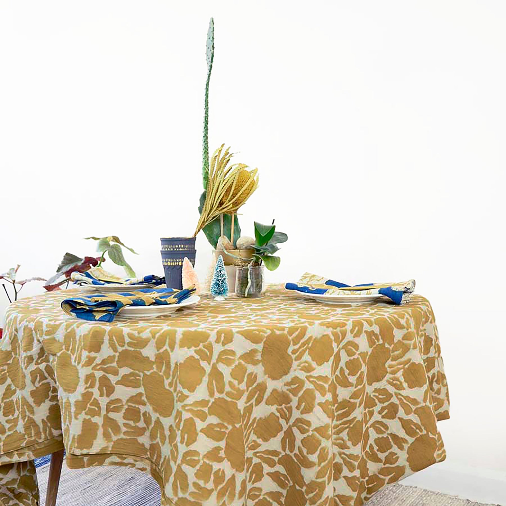 Table setting with a floral tablecloth, plates, and decorative elements on a white background