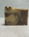Handmade soap bar with brown and beige swirls on a light gray background