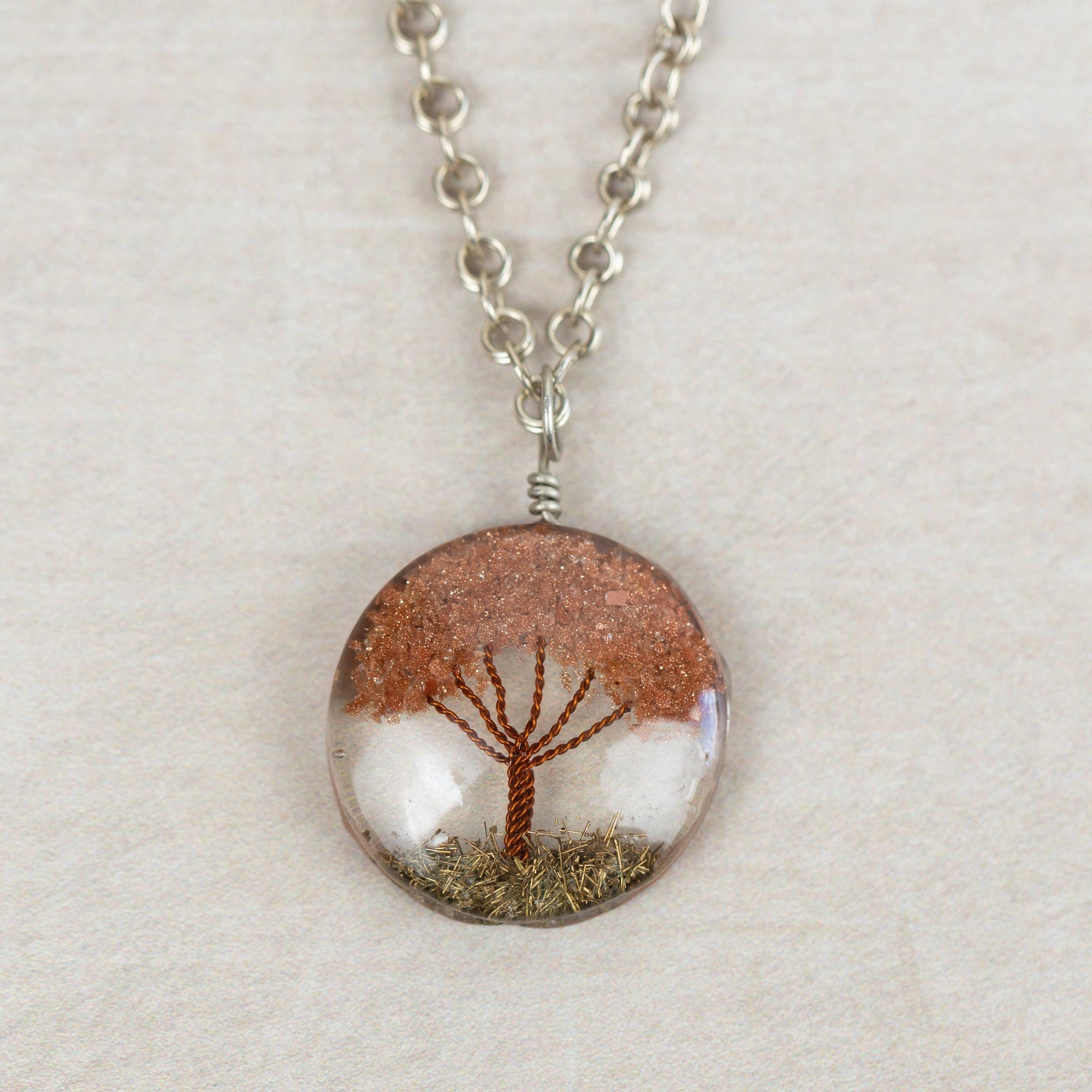 Necklace with a round pendant featuring a tree of life design on a beige background