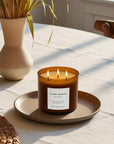 Triple wick candle with 'Slow North' label on a table with a vase and plant in the background