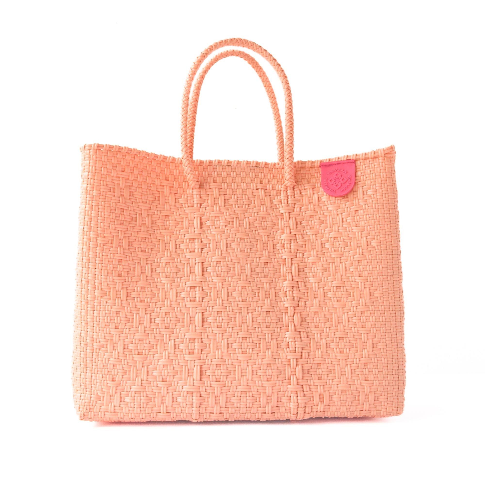 Peach-colored woven tote bag with a pink tag on a white background