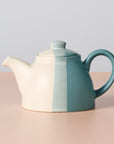 Teapot with two-tone design on a beige surface and light gray background