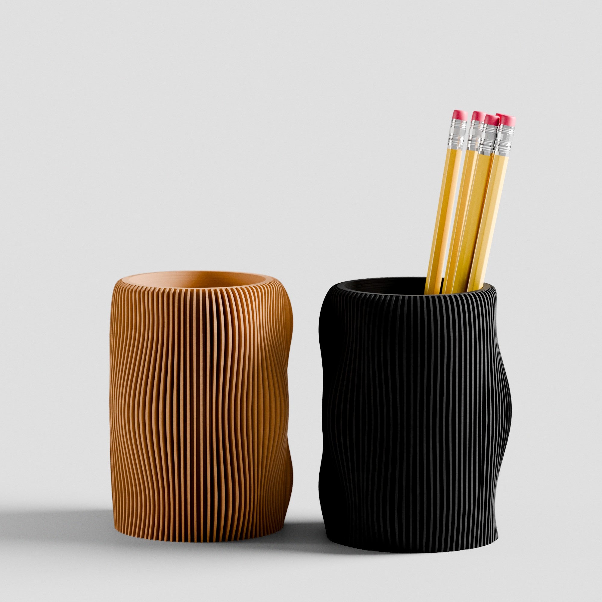 Two textured pen holders, one brown and one black, with pencils inside on a light gray background.