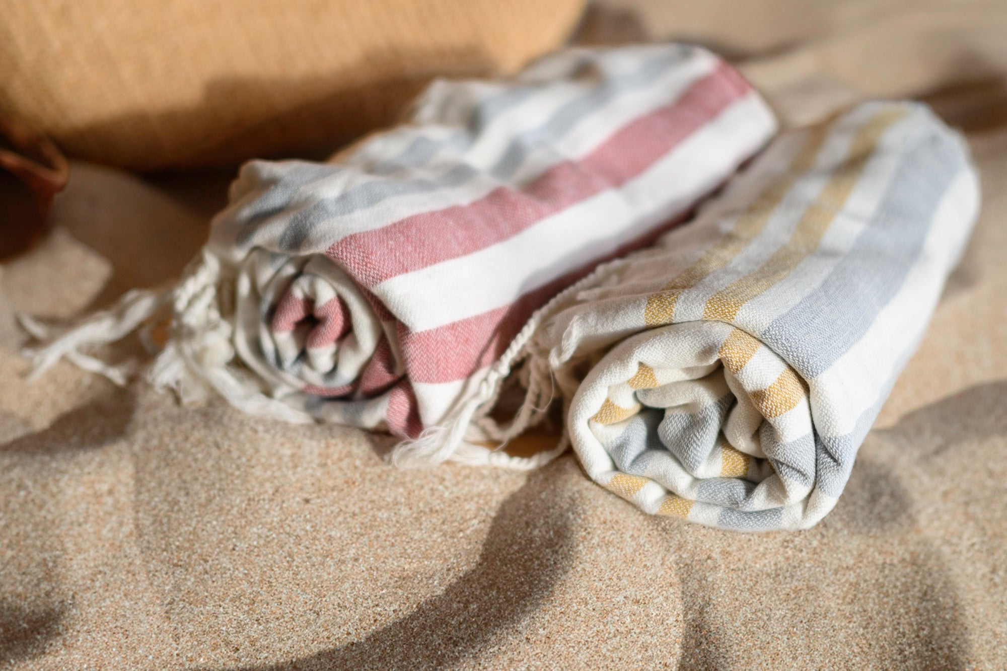 Folded beach towels with stripes and patterns on a sandy surface