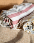 Folded beach towels with stripes and patterns on a sandy surface
