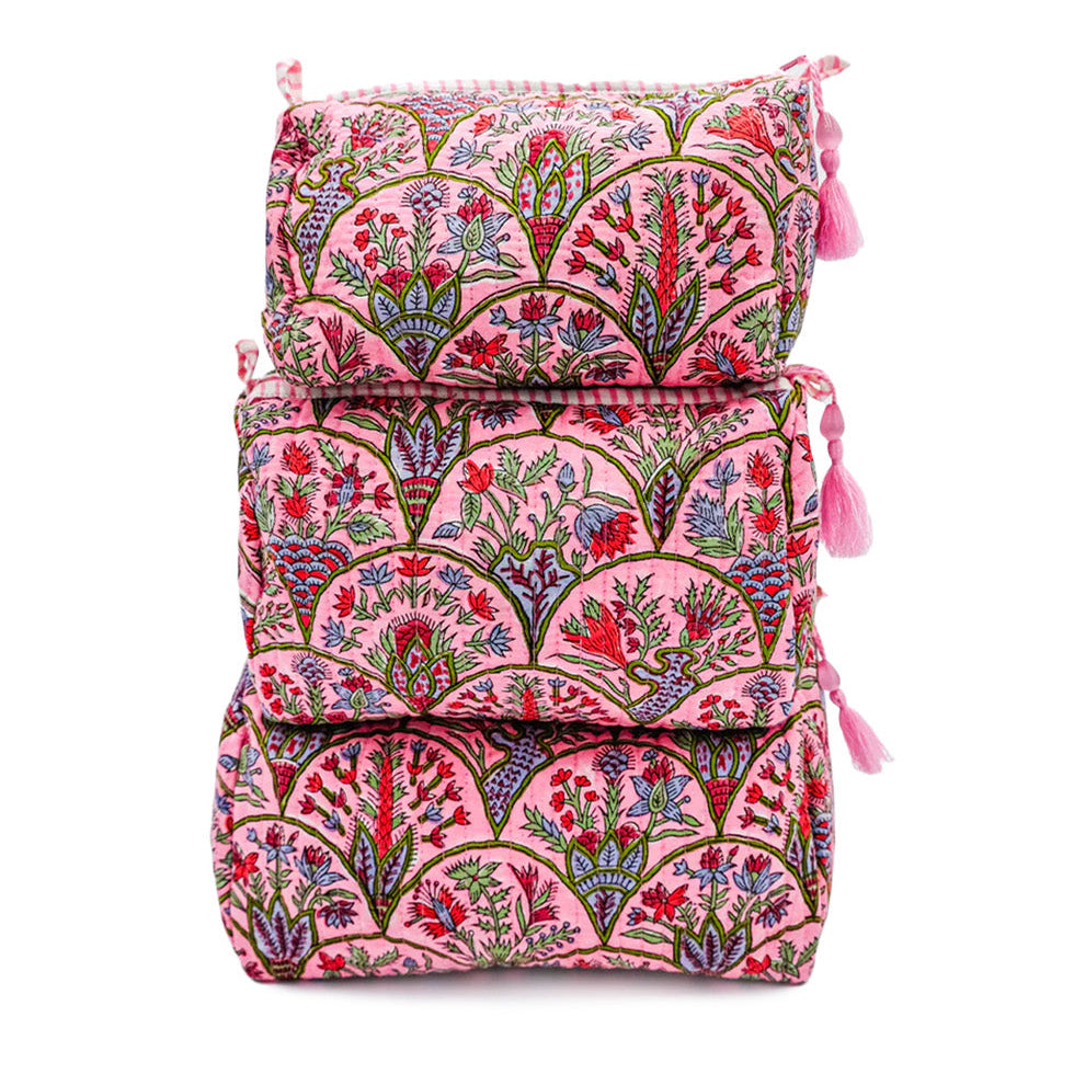 Set of three pink floral travel bags stacked on a white background