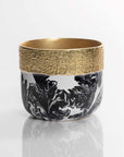 Ceramic cup with gold rim and black abstract design on a white background