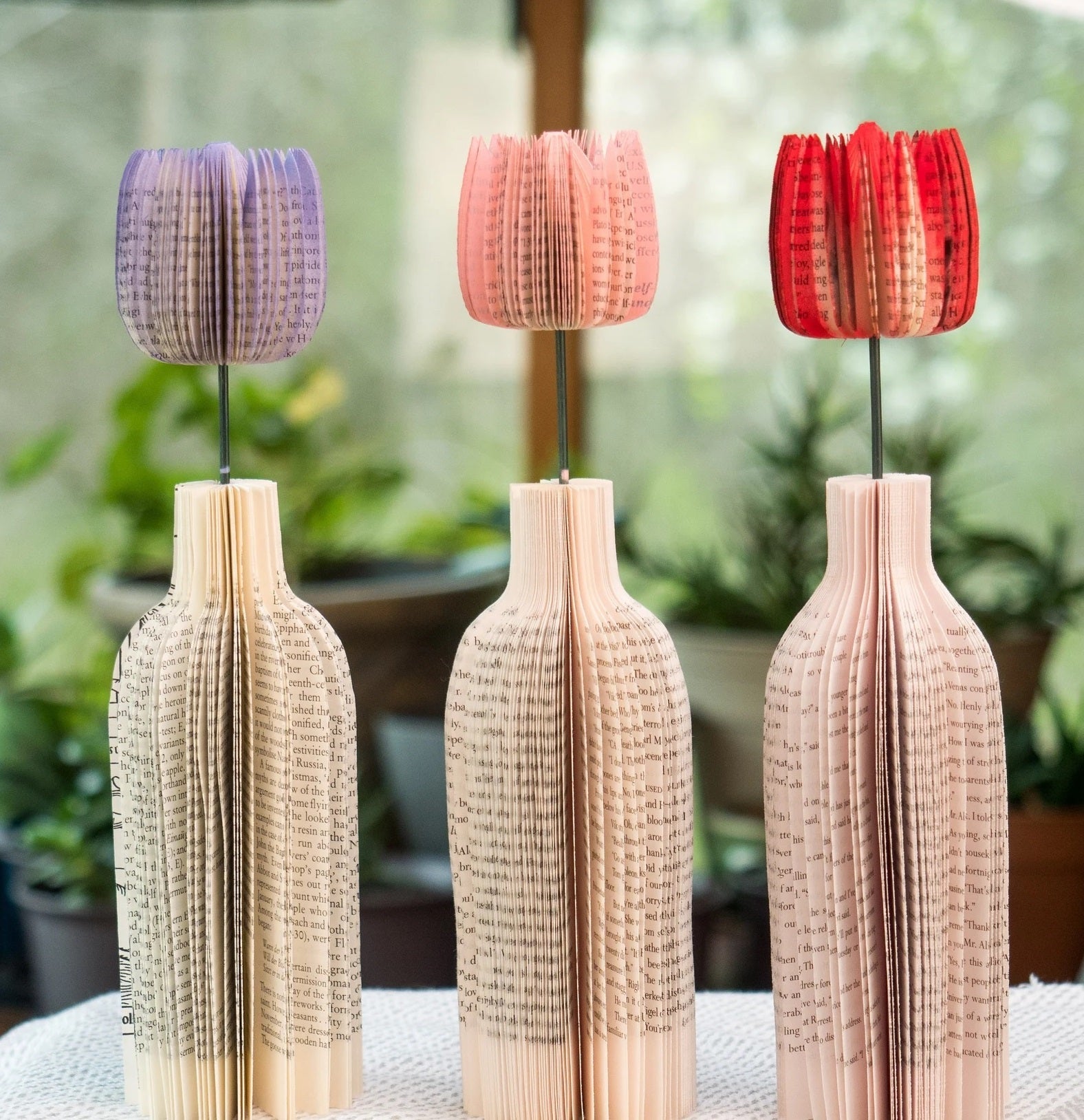 Three decorative paper vases with colorful tulip designed lids on a blurred natural background