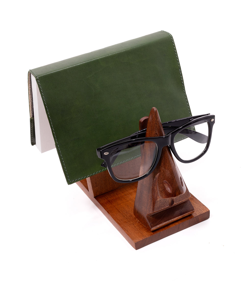 Green leather wallet and black glasses on a wooden stand against a white background