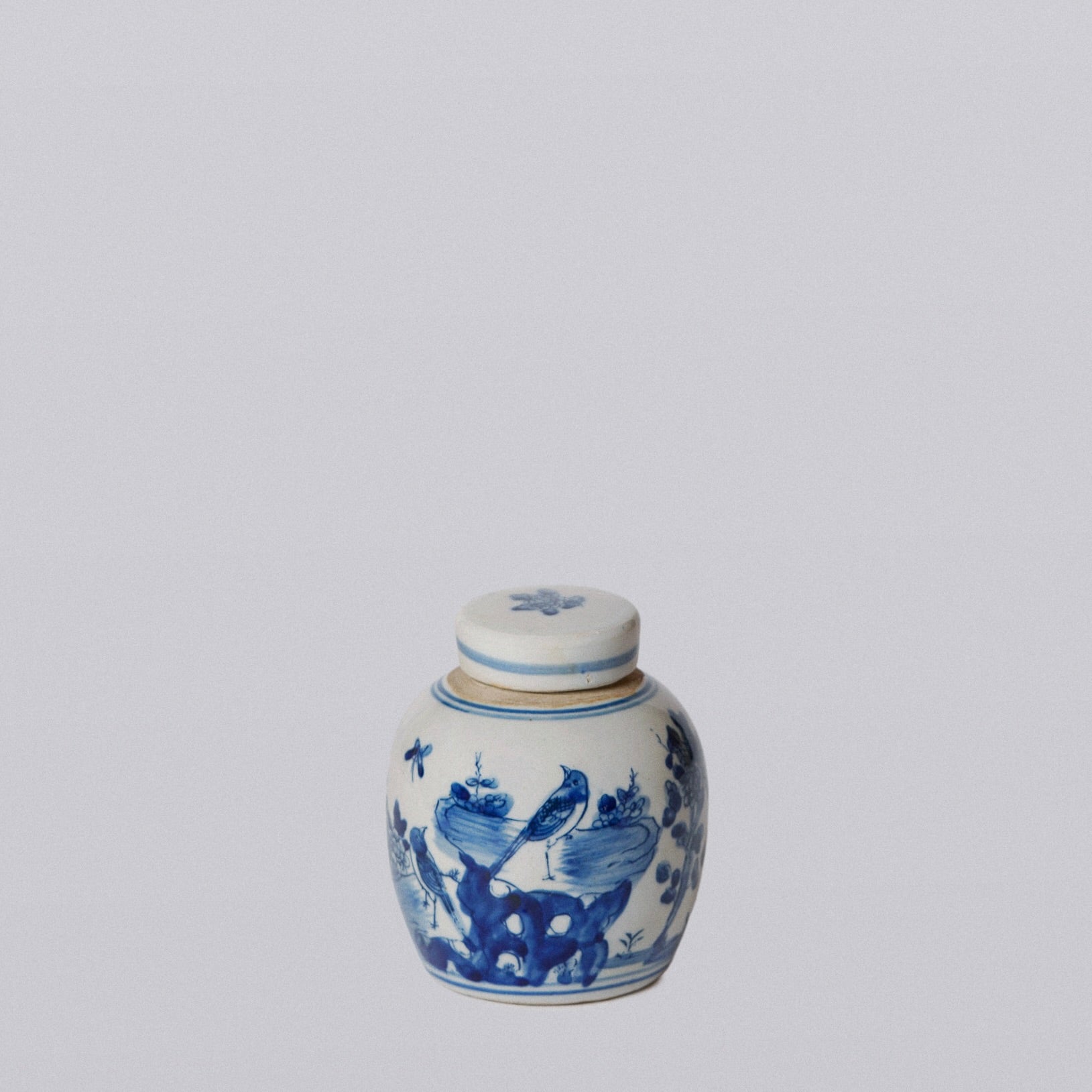 Small ceramic jar with blue floral and bird design on a white background