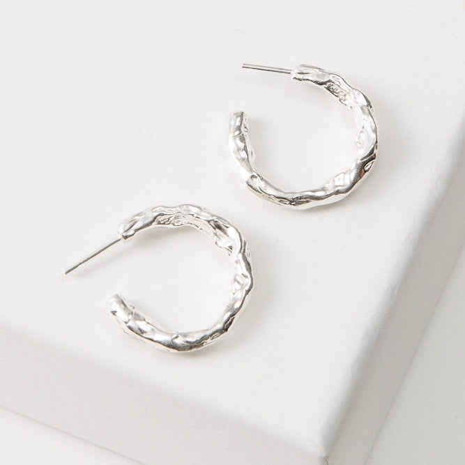 Silver hoop earrings on a white surface