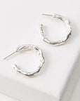 Silver hoop earrings on a white surface