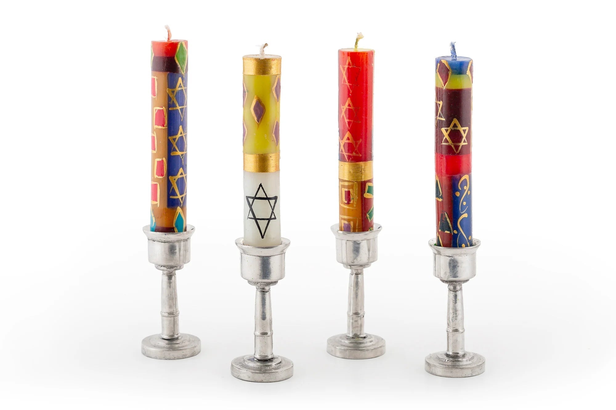 Four colorful candles with star designs in metal candle holders on a white background