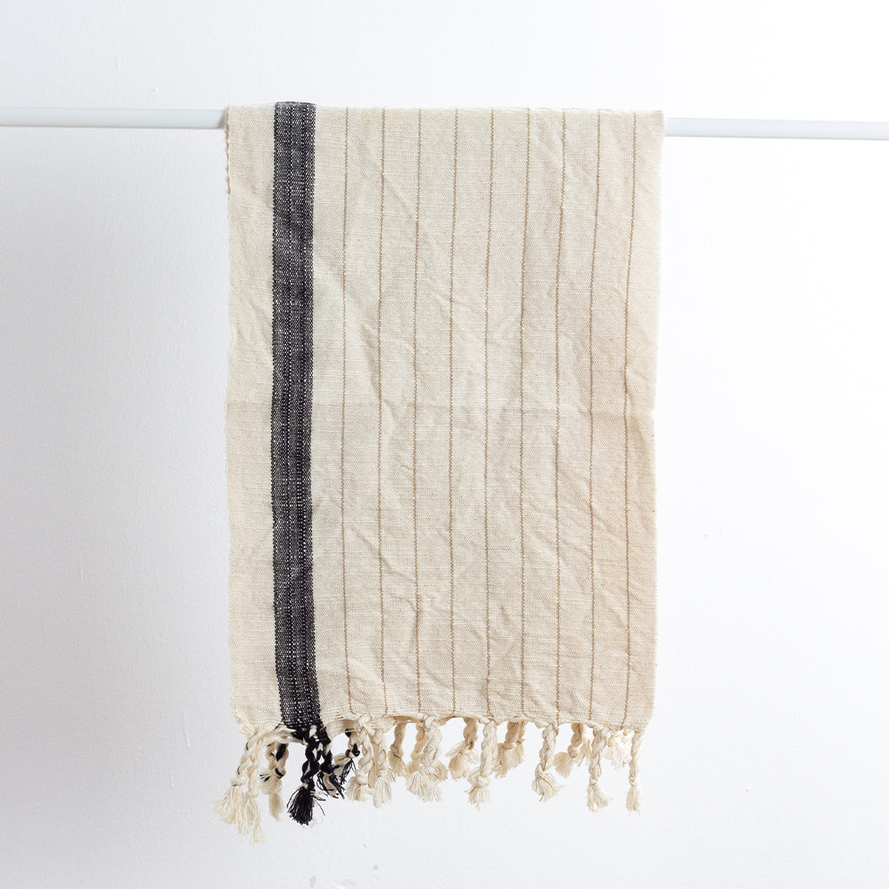 Textured towel with black stripe and fringes on a white background