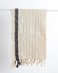 Textured towel with black stripe and fringes on a white background