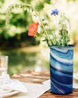 Blue glass vase with flowers on a table outdoors
