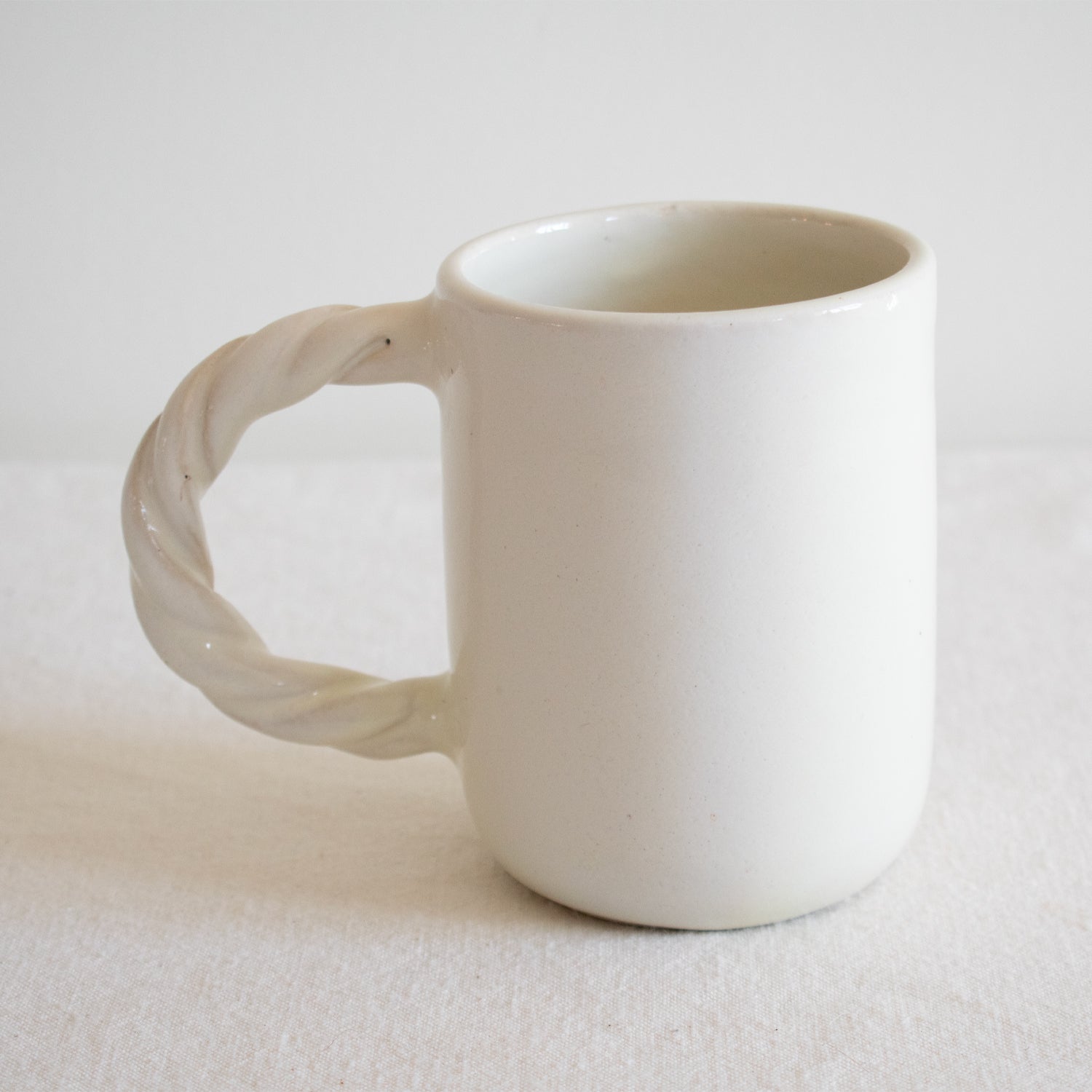 White ceramic mug with a textured handle on a white background